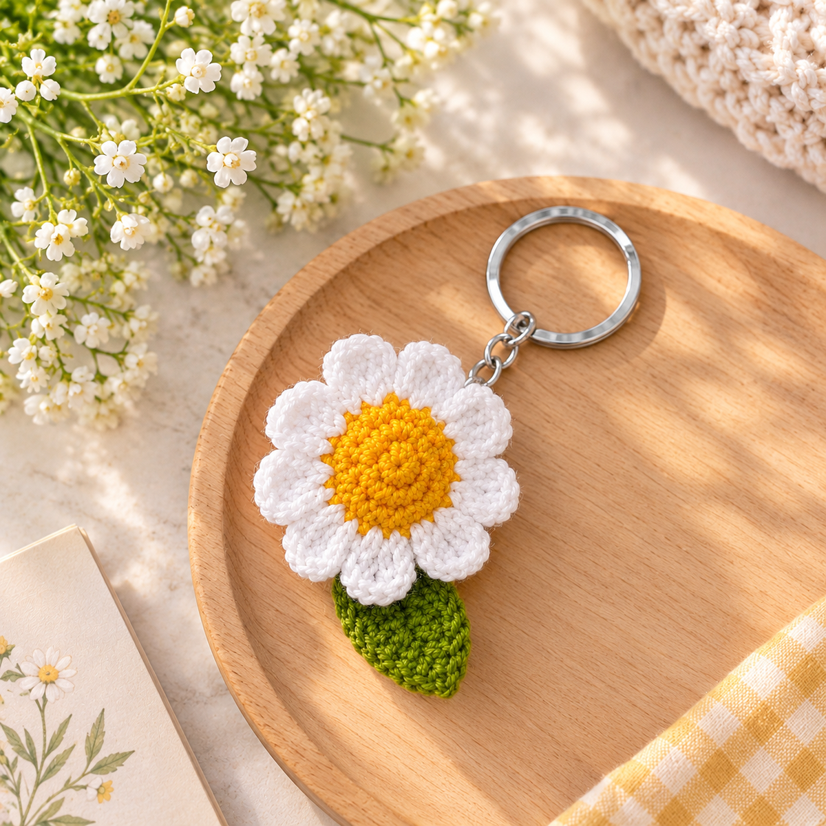 Handmade crochet daisy flower keychain with white petals, yellow center and green leaf